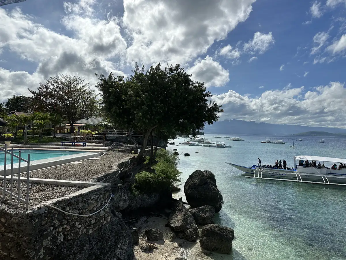 A Moalboal cove: rocks, clear shallows, a dive boat