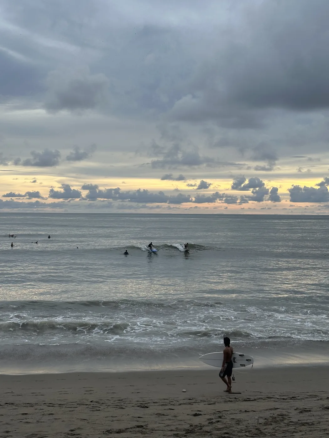 A surfer on the Canggu shore at dusk