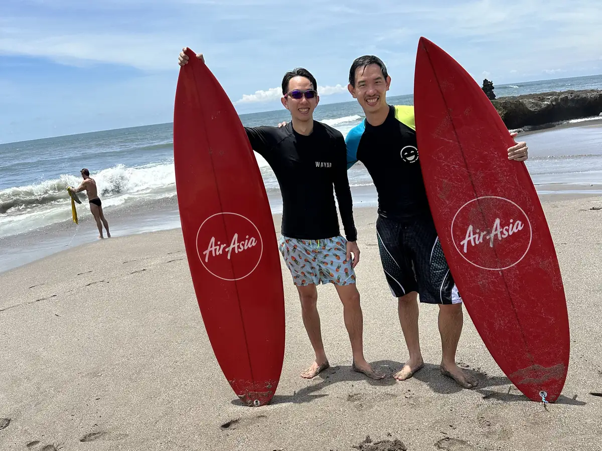 Two surfers with red surfboards on the beach at Canggu, Bali