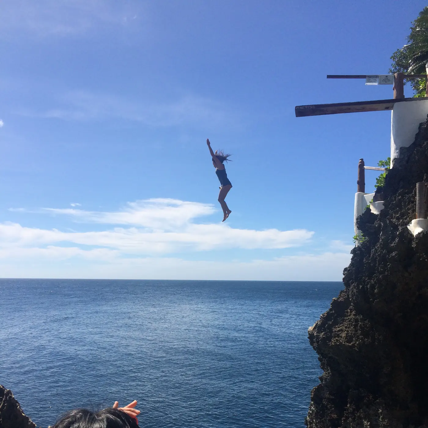 A diver in mid-air off the high platform, open sea below