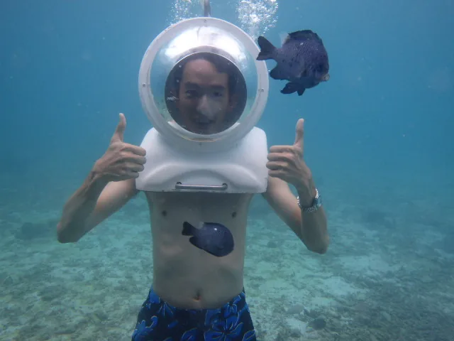 Helmet diving on the sea floor, thumbs up, fish around