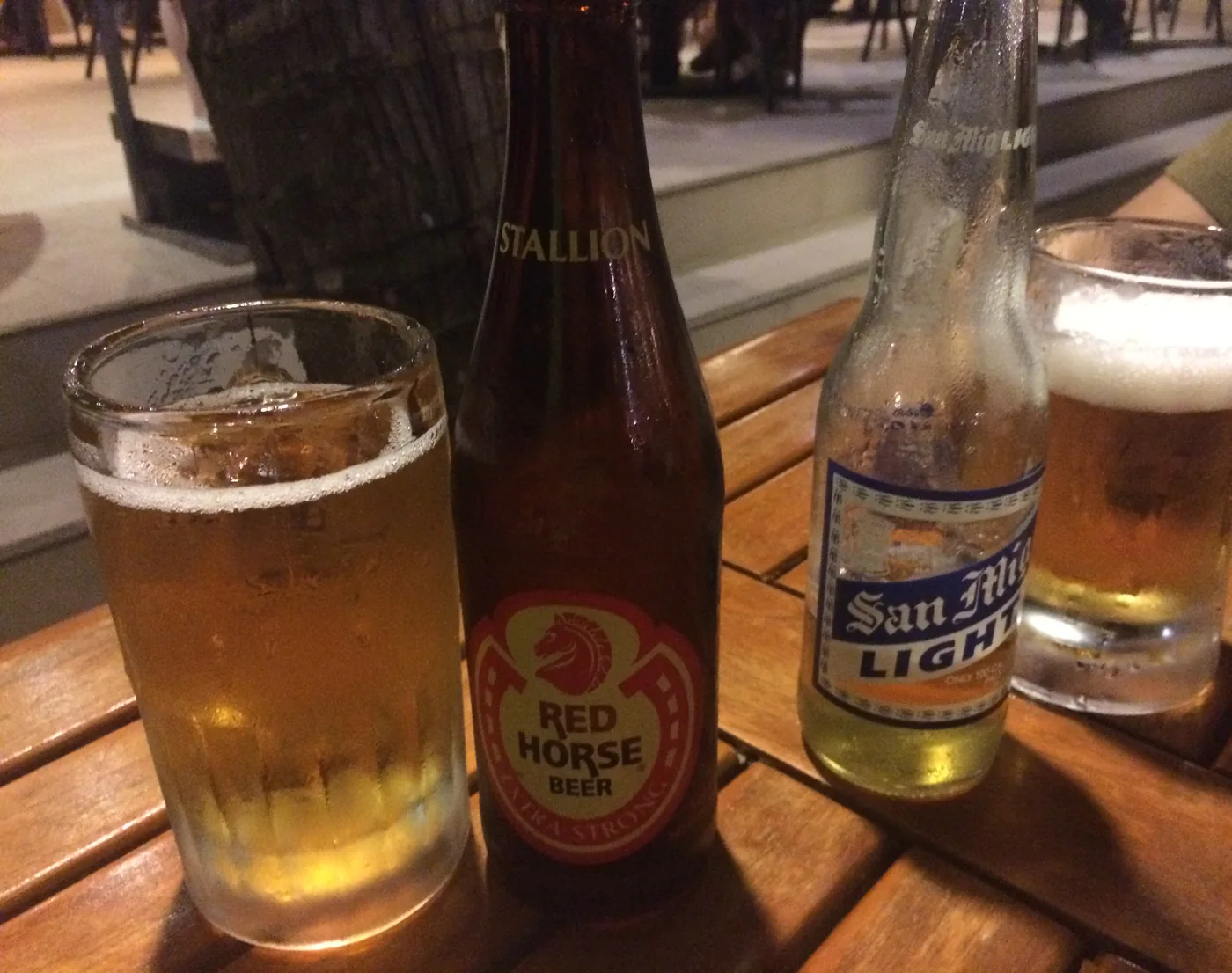 Red Horse and San Miguel beers on a beach bar table