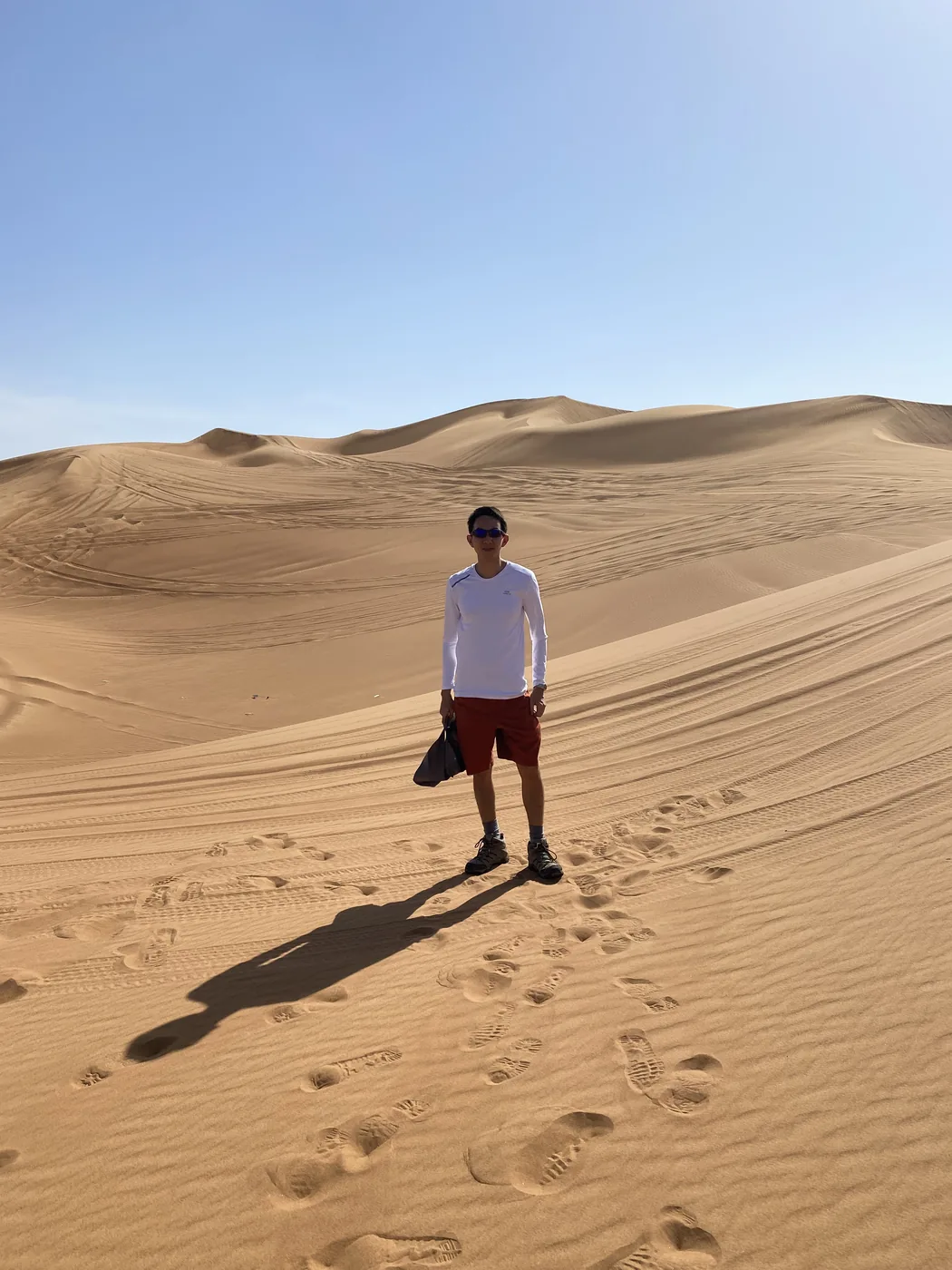 Spencer standing among tall sand dunes on a desert safari outside Dubai