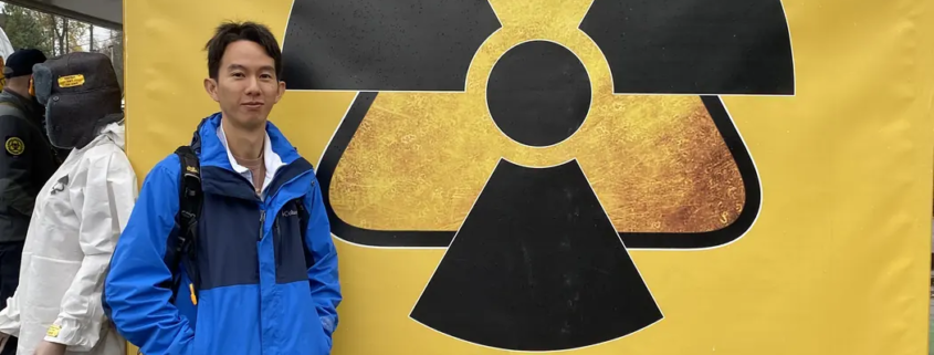 Spencer Li in front of a yellow radiation symbol banner at the Dytyatky checkpoint into the Chernobyl zone