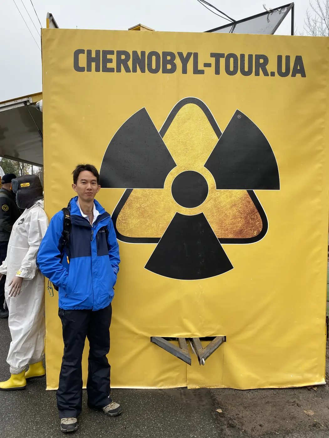 Spencer Li in front of a yellow radiation symbol banner at the Dytyatky checkpoint into the Chernobyl zone