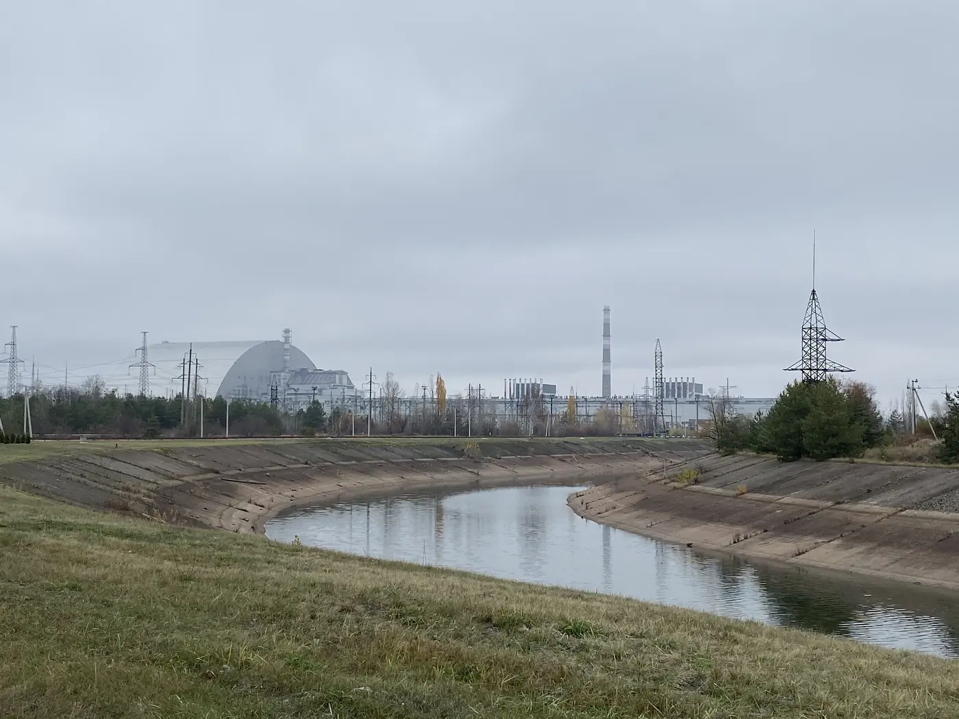 The Chernobyl power plant and the steel arch over Reactor 4, seen across the cooling canal