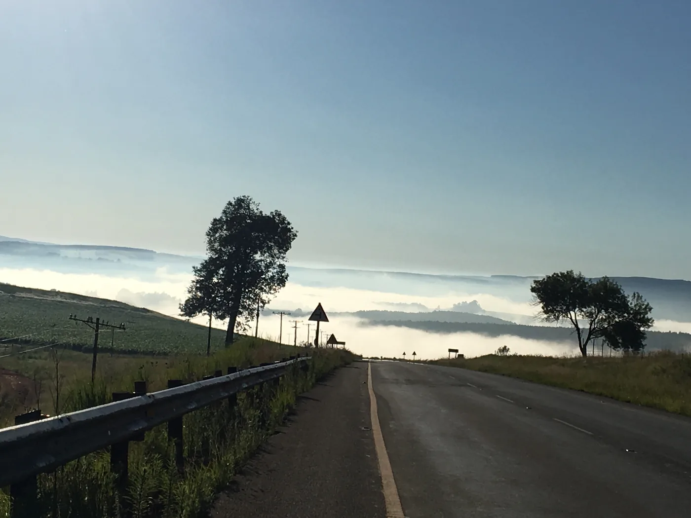 An empty dawn road, mist in the valley