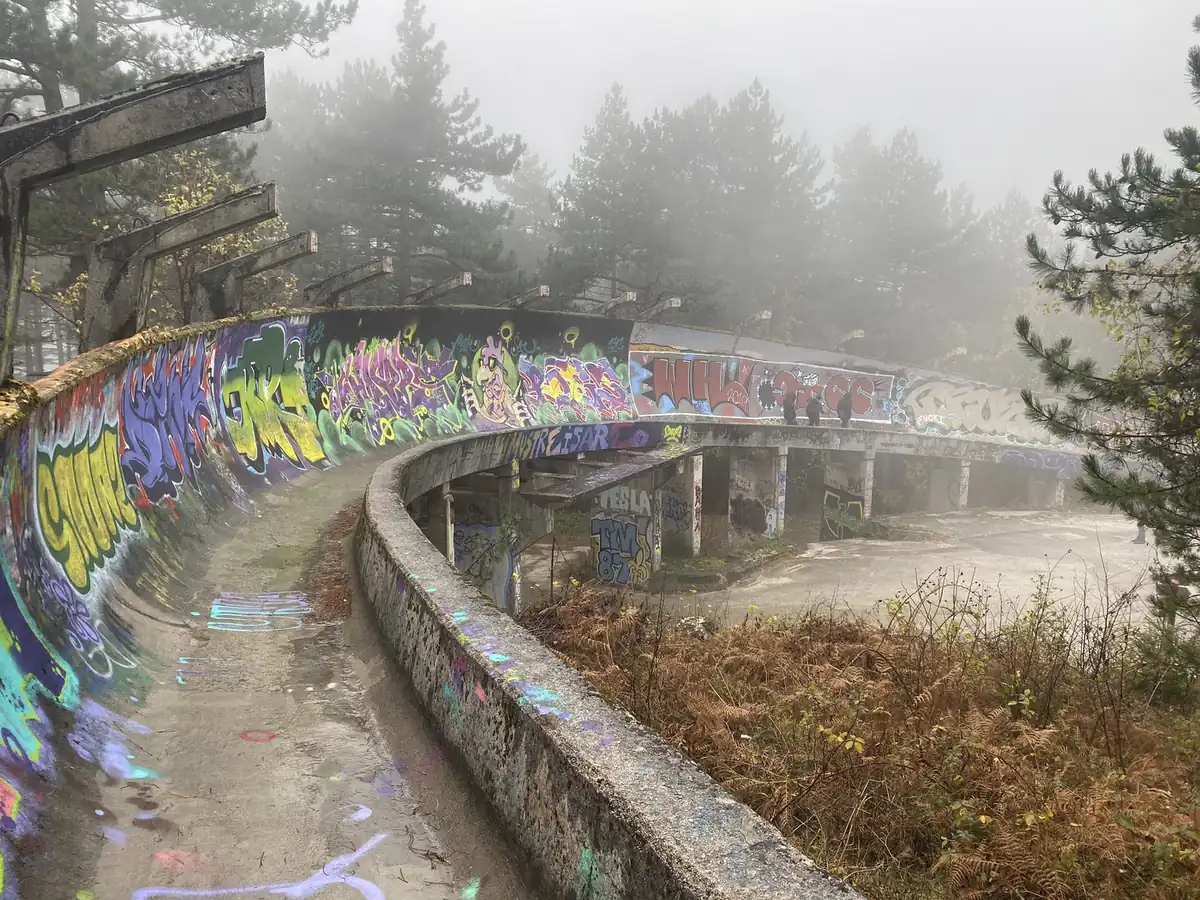 A graffiti-covered curve of the Olympic bobsleigh track in fog
