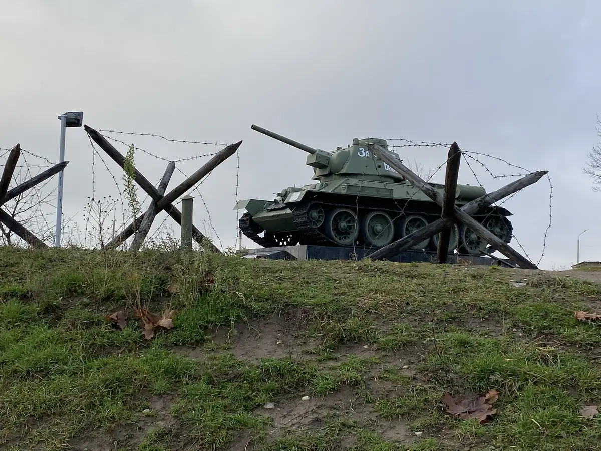 A T-34 tank behind barbed wire and anti-tank hedgehogs, the Stalin Line