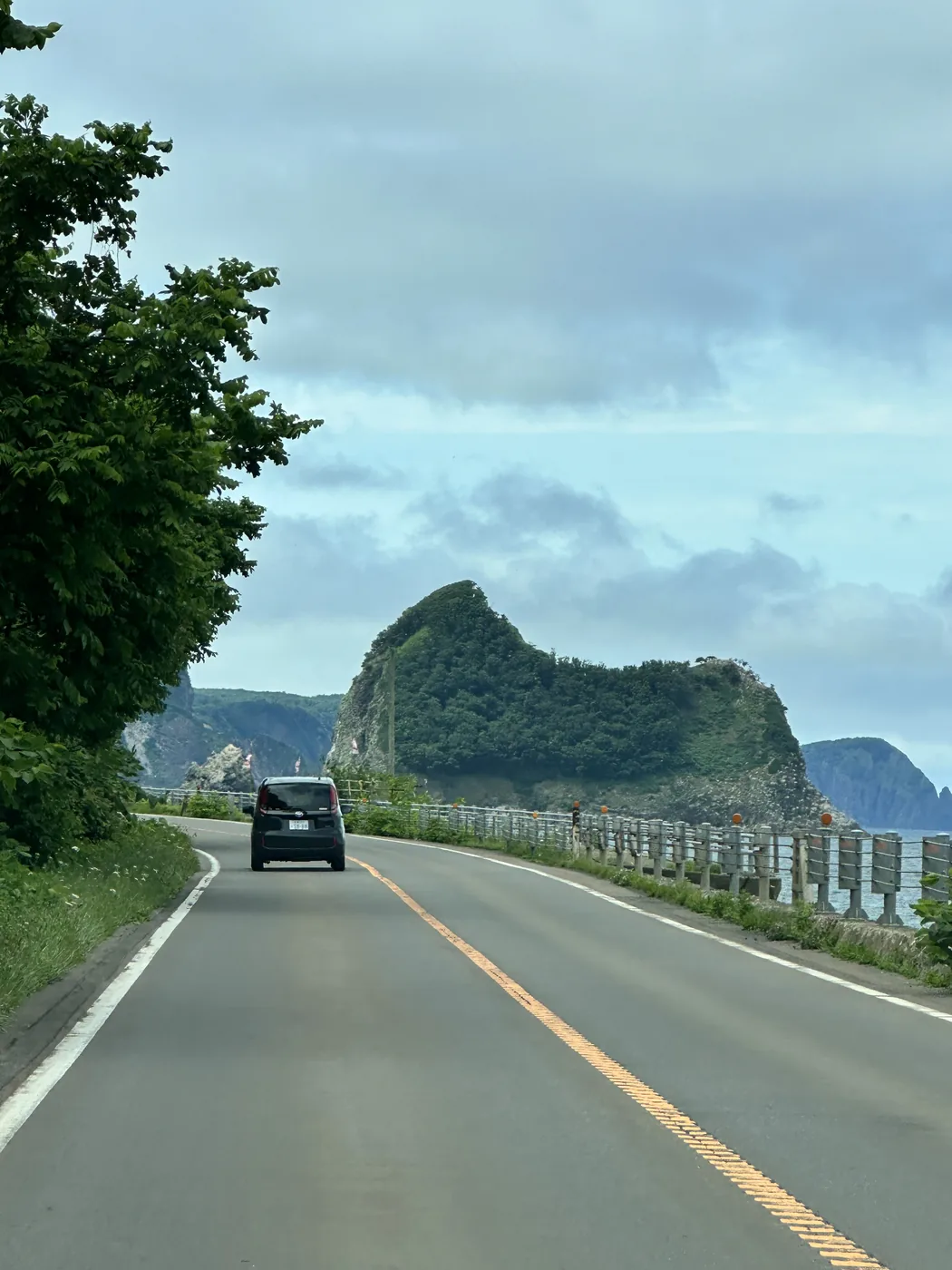 The Shakotan coast road, a car ahead, a sea stack
