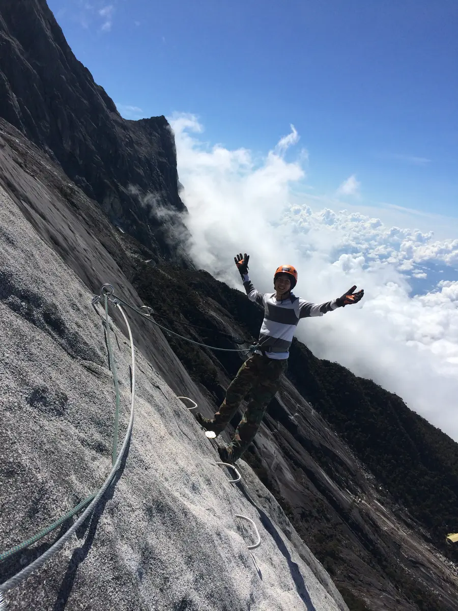 A climber on the via ferrata, clouds below