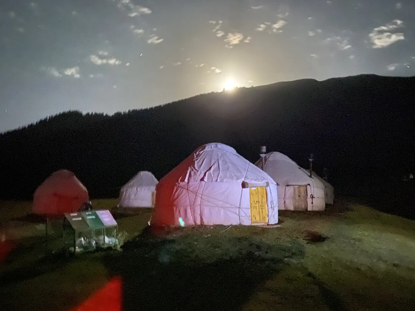 Yurts lit up at night under the moon in the Jeti-Oguz valley