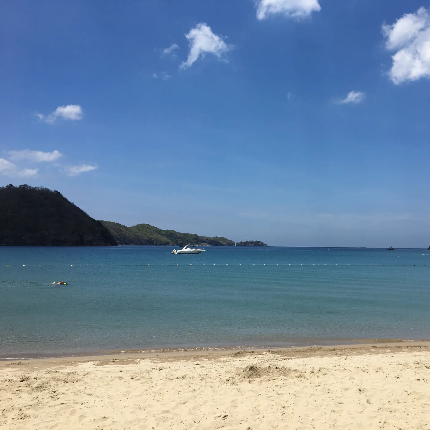 A sandy cove between two green headlands on the Batangas coast