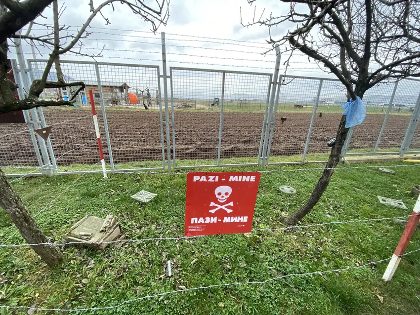 A red Pazi Mine warning sign behind a wire fence at the Tunnel of Hope museum
