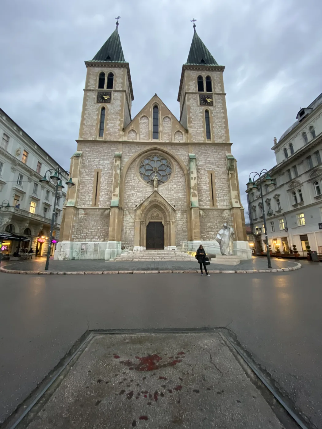 The twin towers of the Sacred Heart Cathedral in Sarajevo, with a Sarajevo rose on the pavement in front