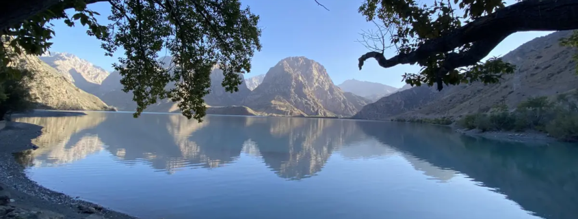 Iskanderkul lake reflecting the Fann Mountains in still water, Tajikistan