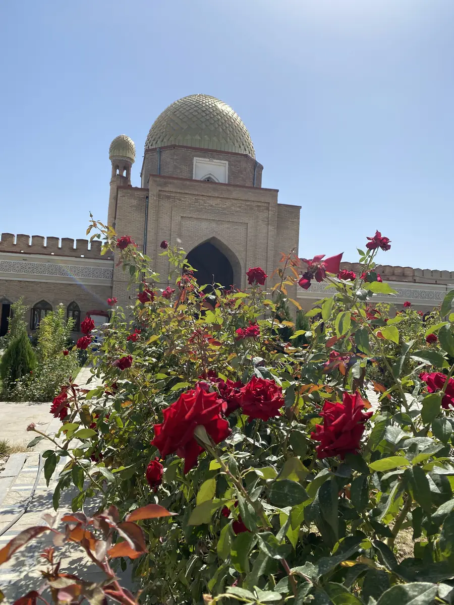The blue-domed gateway on Mug Teppe with red roses in front, Istaravshan