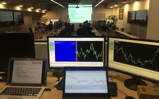 A trading desk with charts on three screens