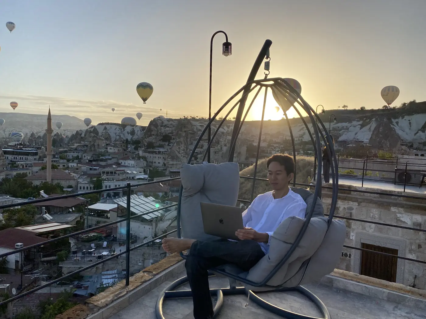 Trading on my laptop at sunrise in Cappadocia, with hot-air balloons behind
