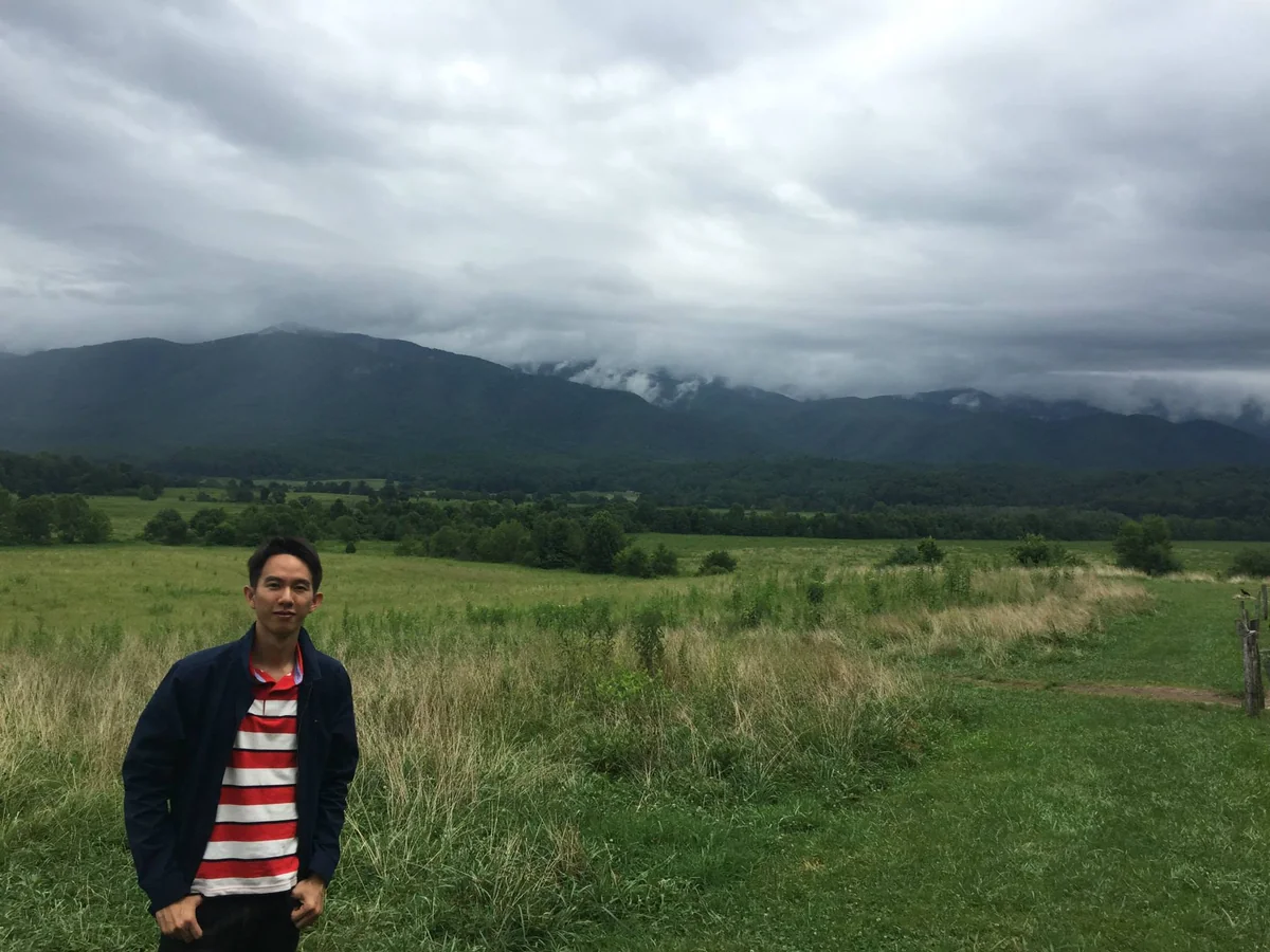 Spencer in a meadow in the Great Smoky Mountains, with cloud low on the ridges