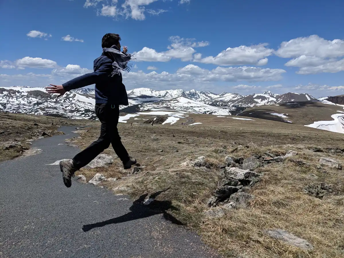 Spencer mid-leap on the road above the snowfields of Rocky Mountain National Park